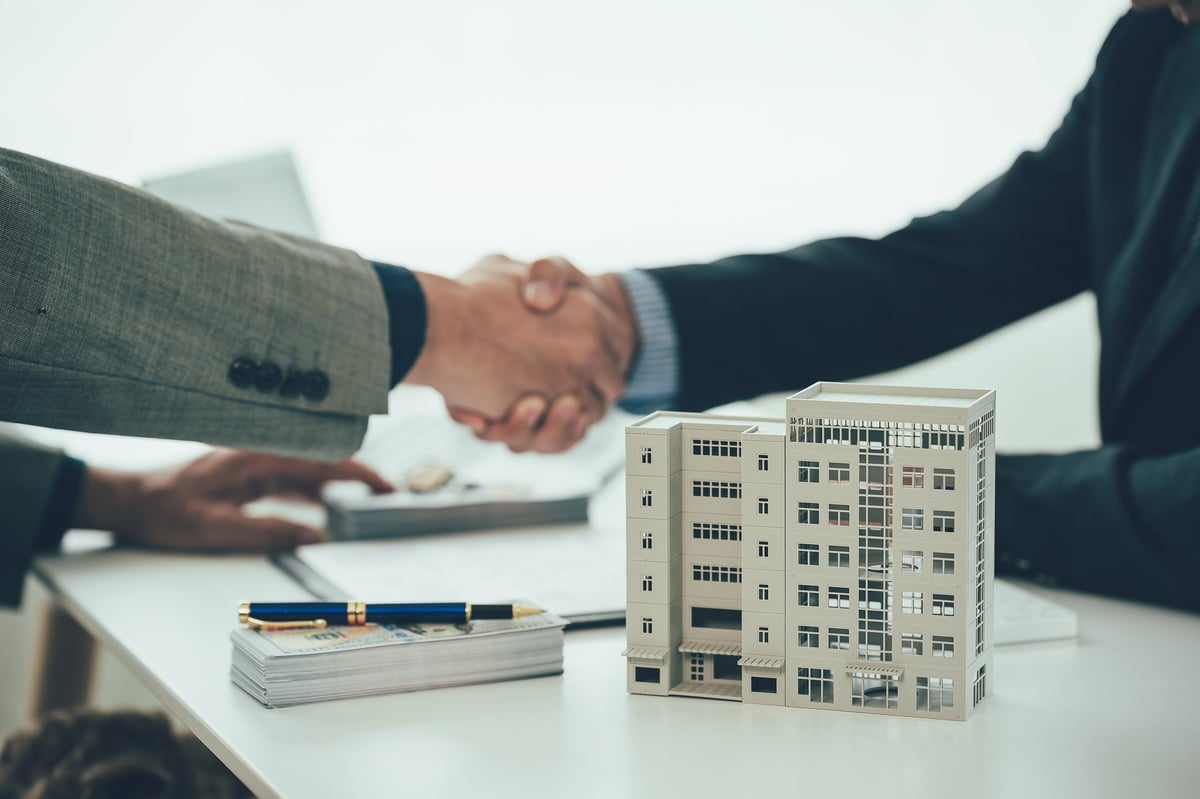 Two people shaking hands across a table after a successful real estate transaction