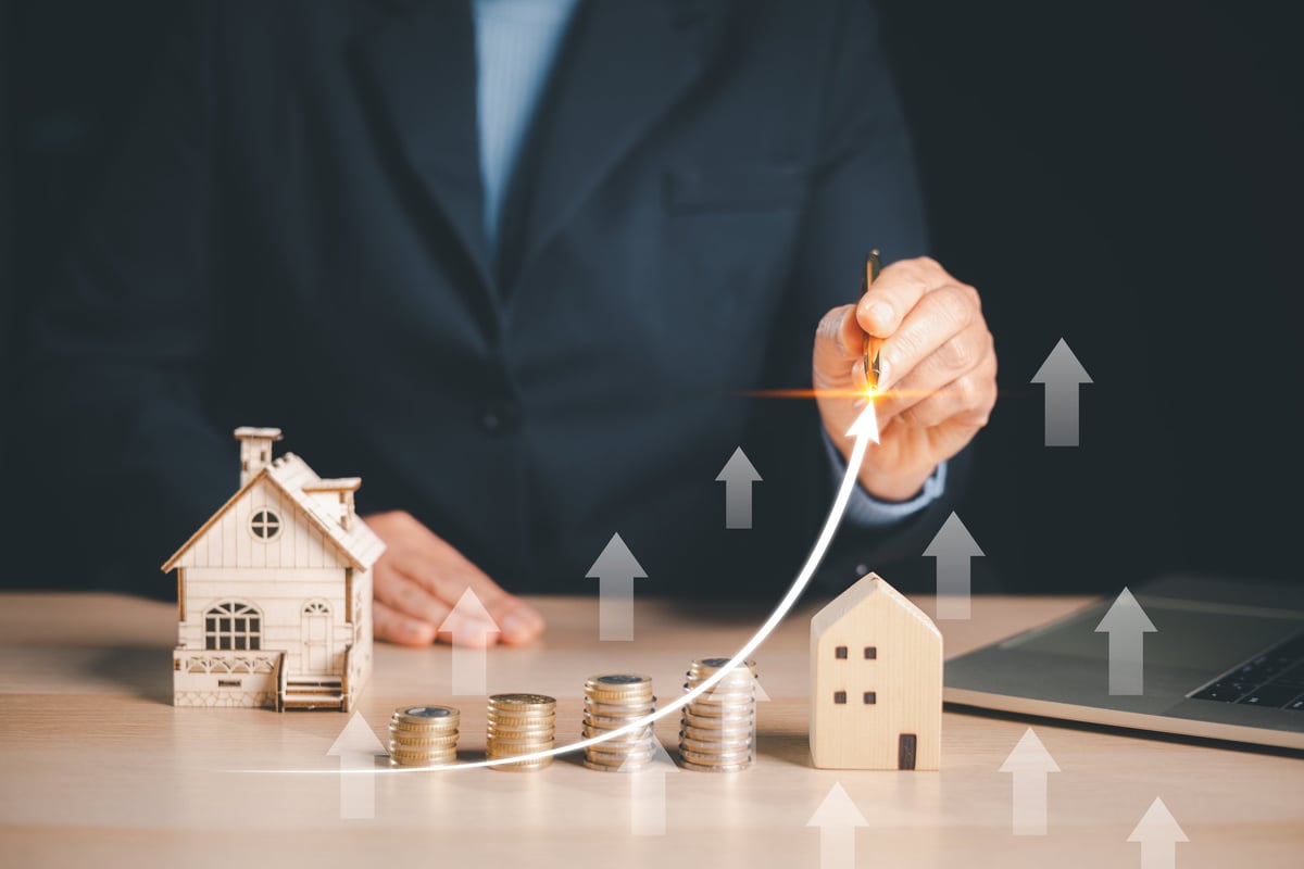 Drawing a rising arrow over a property model, symbolizing real estate growth and planning